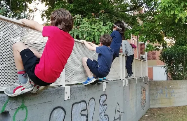 Gruppo di bambini che attraversano un muro lateralmente stando appesi